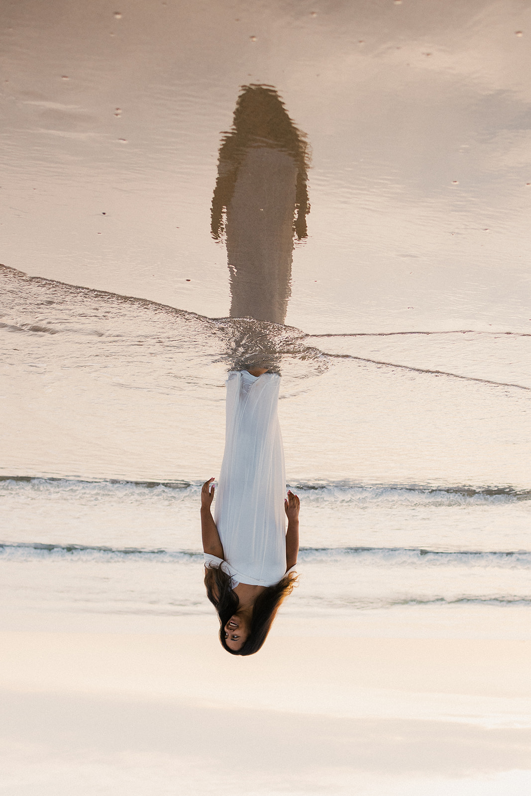 Vrouw aan het water, spiegelbeeld in nat zand